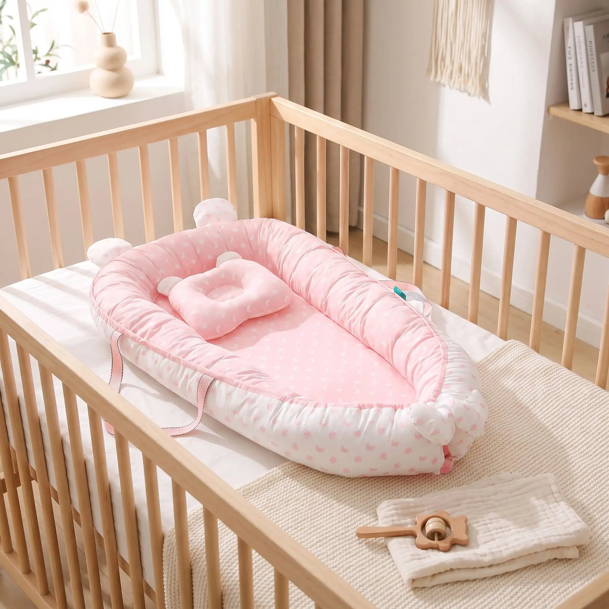 couffin bébé rose dans un llit à barreaux